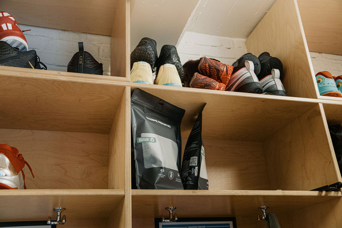 Locker-room shelves full of training shoes, with a Shape Regime pouch on the middle shelf